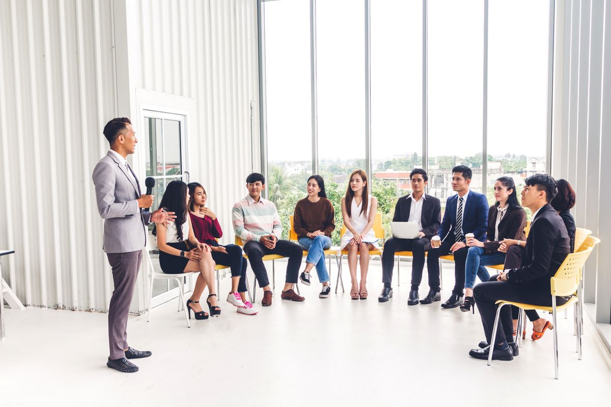 Businessman,Standing,In,Front,Of,Group,Of,People,In,Consulting